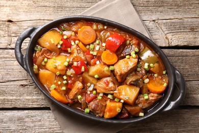 Photo of Delicious stew with vegetables in baking dish on wooden table, top view