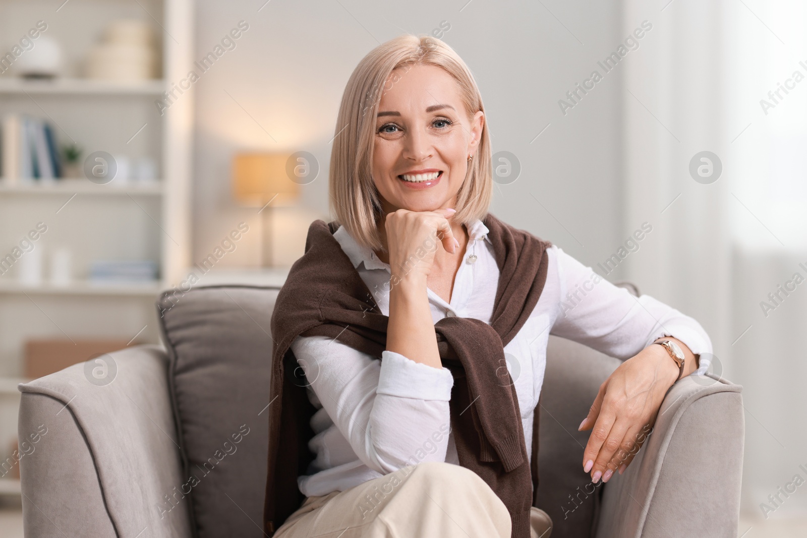 Photo of Portrait of smiling middle aged woman sitting on armchair at home