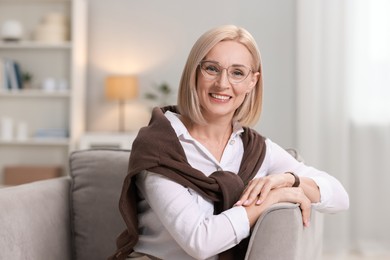 Photo of Portrait of smiling middle aged woman sitting on armchair at home