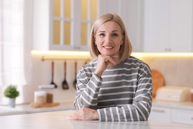 Photo of Portrait of smiling middle aged woman in kitchen