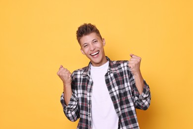 Portrait of happy young student on yellow background