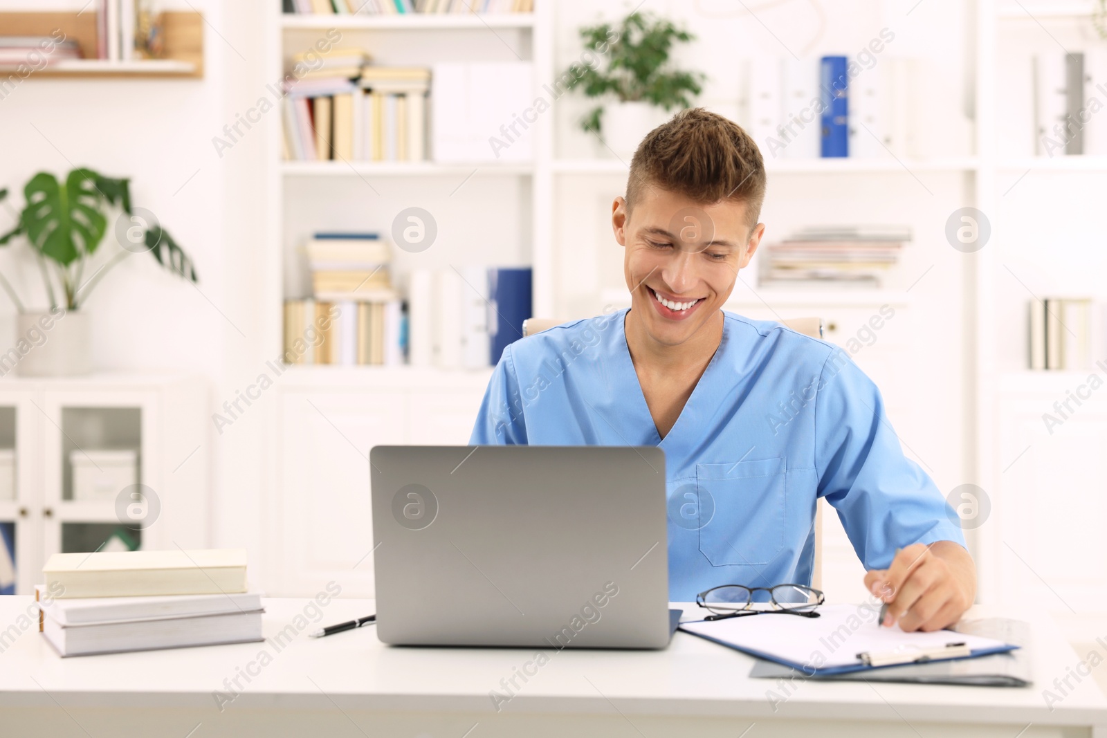 Photo of Medical student in uniform studying at table indoors