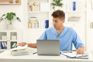 Photo of Medical student in uniform studying at table indoors