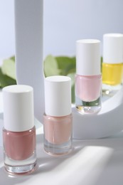 Photo of Stylish presentation of nail polishes in bottles on white table