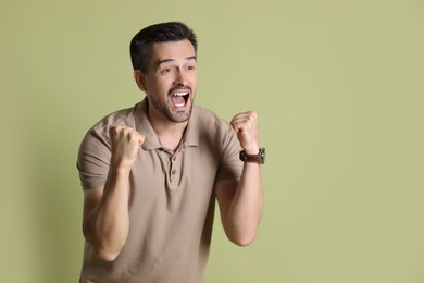 Portrait of happy winner on pale olive background, space for text