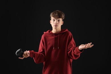 Teenage boy with controller on black background