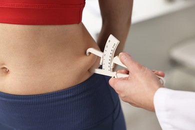 Photo of Doctor measuring woman's body fat with caliper in clinic, closeup