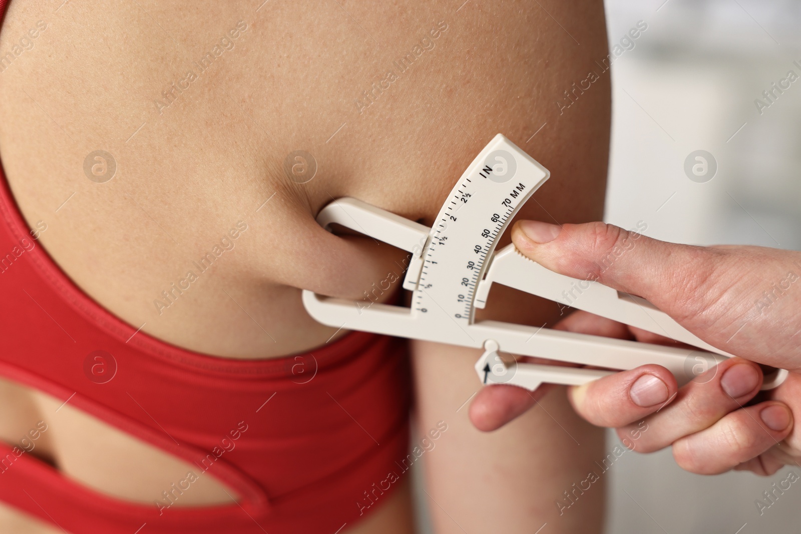 Photo of Doctor measuring woman's body fat with caliper in clinic, closeup