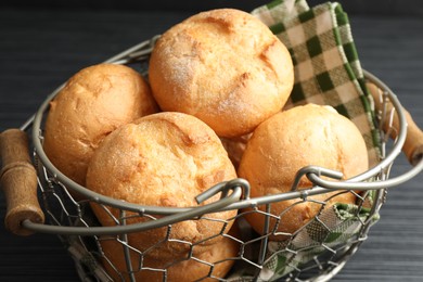 Photo of Metal basket with homemade tasty buns on black table, closeup