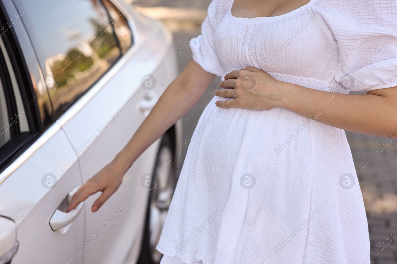 Photo of Pregnant woman opening car door outdoors, closeup