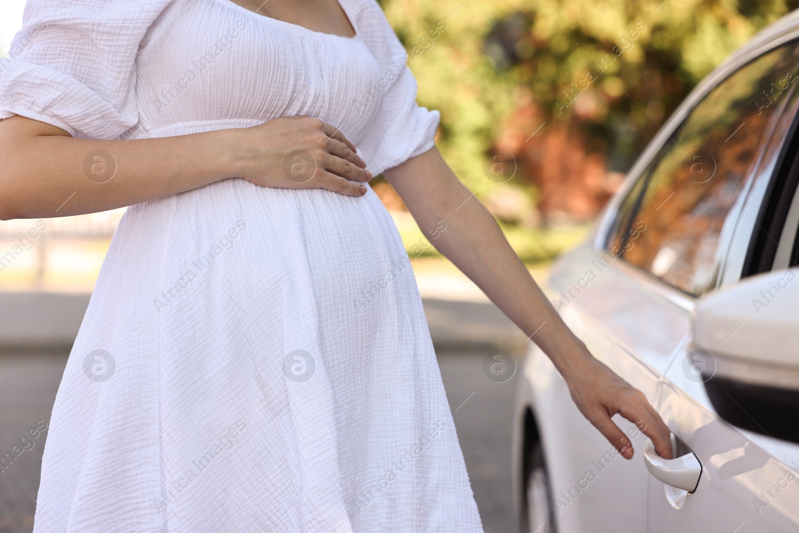 Photo of Pregnant woman opening car door outdoors, closeup