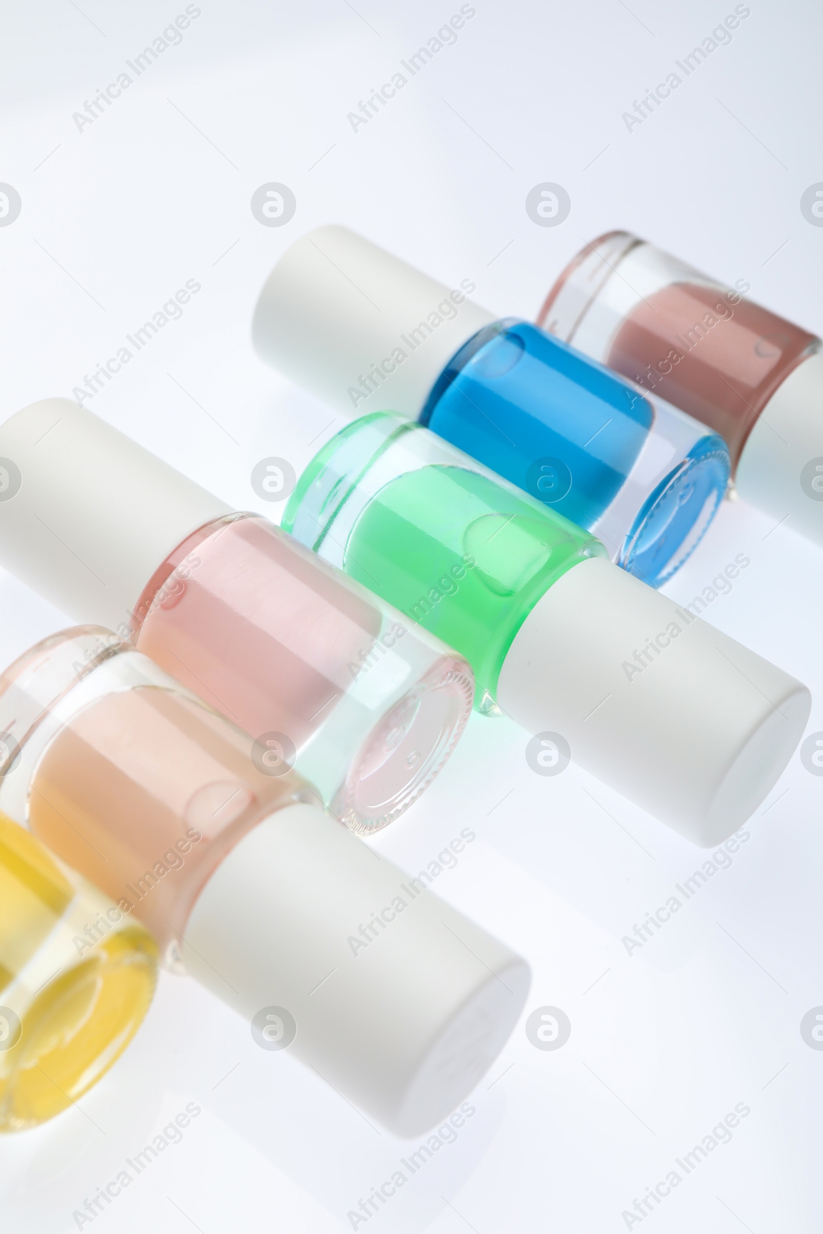 Photo of Nail polishes in bottles on white background, closeup