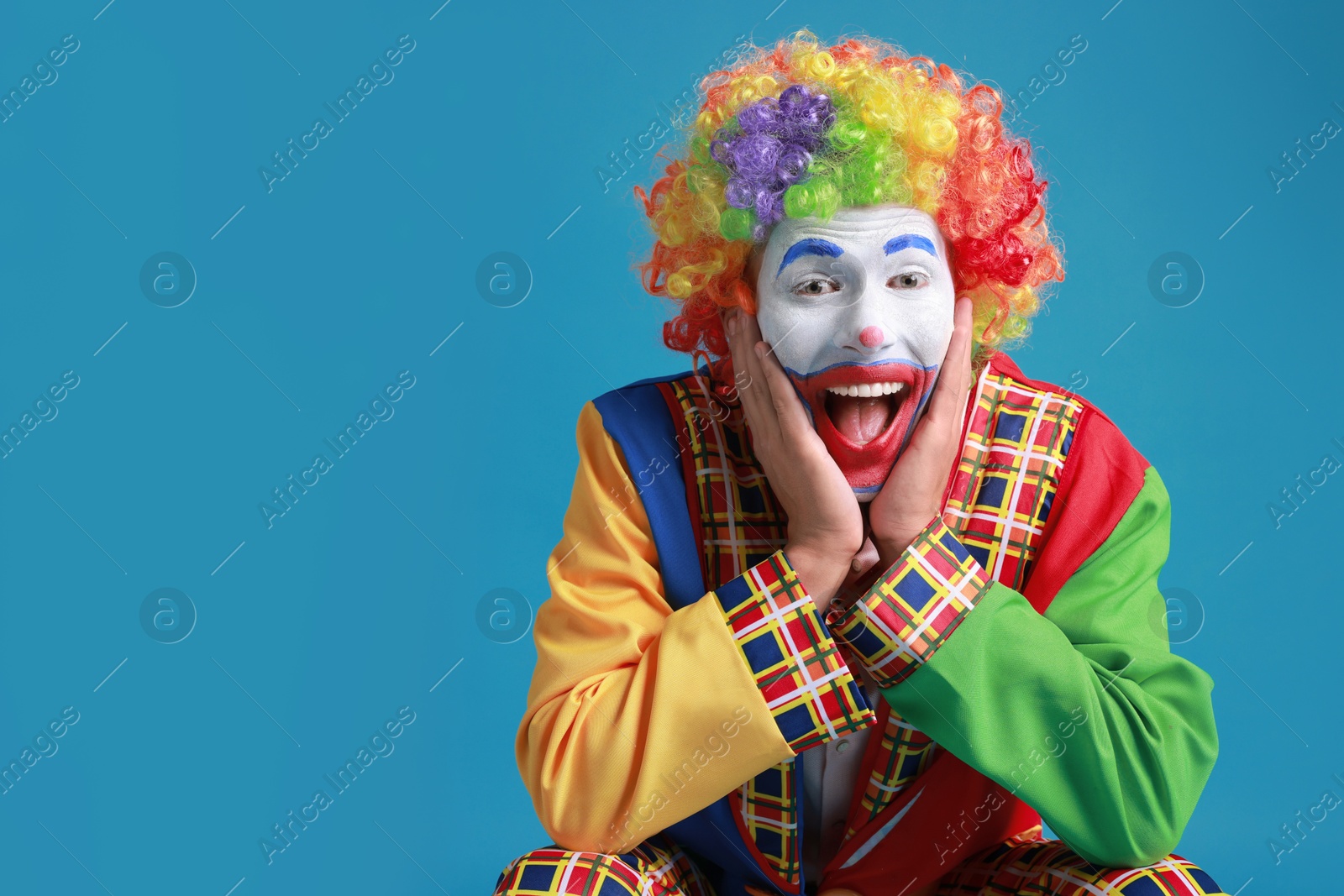 Photo of Happy clown on blue background, space for text