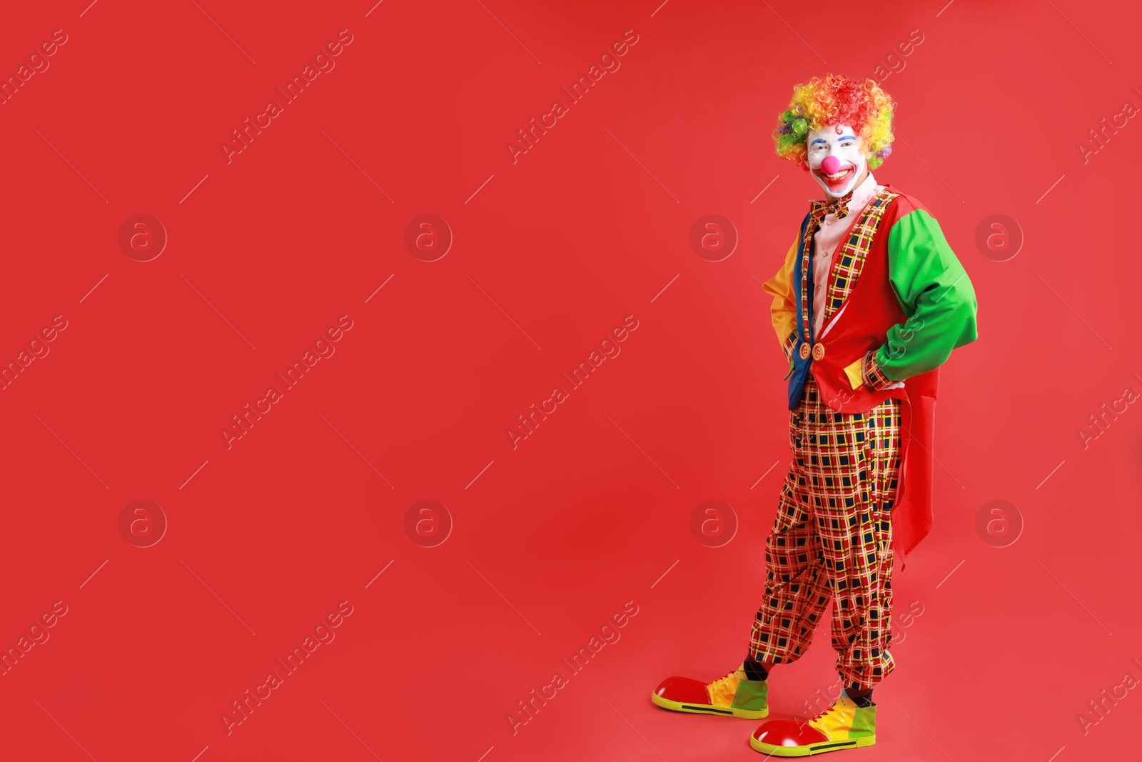 Photo of Portrait of happy clown on red background, space for text