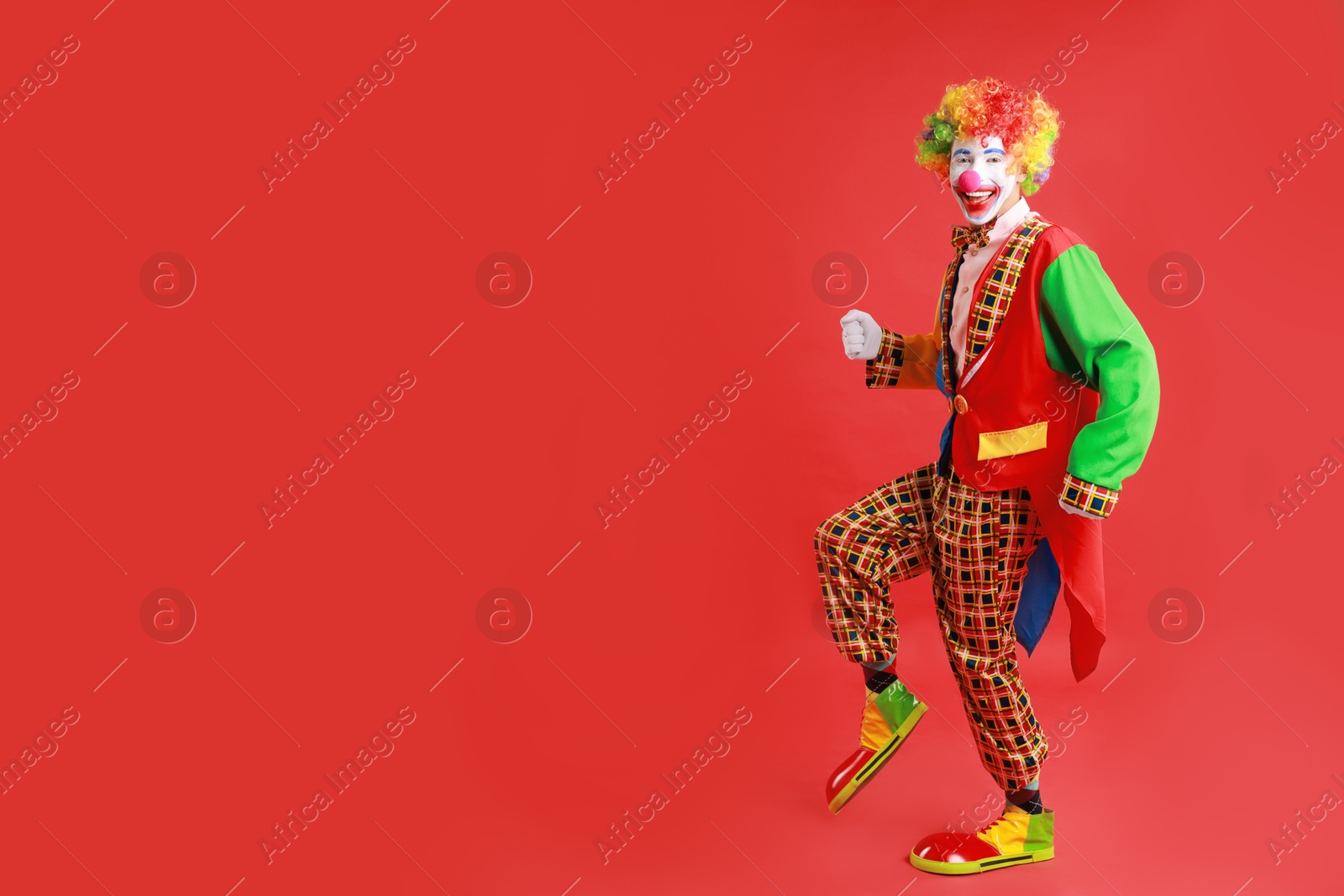 Photo of Portrait of happy clown on red background, space for text