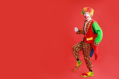 Portrait of happy clown on red background, space for text