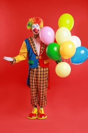 Happy clown with colorful balloons on red background