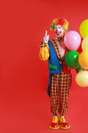 Happy clown with colorful balloons on red background, space for text