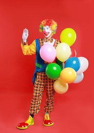 Photo of Happy clown with colorful balloons on red background