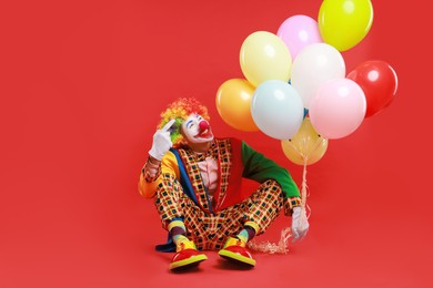 Happy clown with colorful balloons on red background