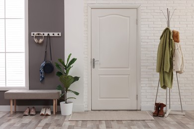 Photo of Stylish hallway interior with clothing rack and houseplant