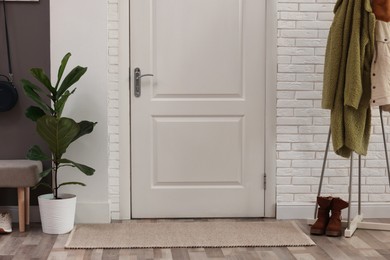 Photo of Stylish hallway interior with clothing rack and houseplant