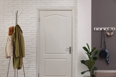 Photo of Stylish hallway interior with clothing rack and houseplant