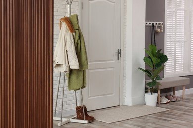 Photo of Stylish hallway interior with clothing rack and houseplant