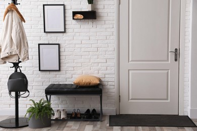 Photo of Stylish hallway interior with coat rack and bench