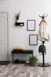 Photo of Stylish hallway interior with coat rack and bench