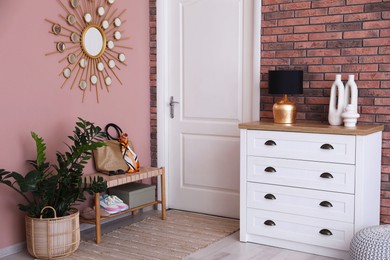 Photo of Stylish hallway interior with chest of drawers and bench