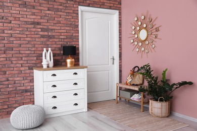 Photo of Stylish hallway interior with chest of drawers and bench