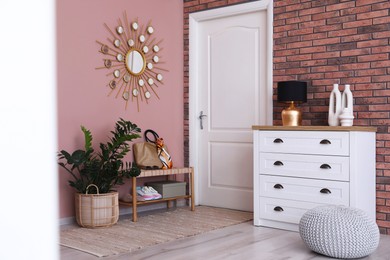 Photo of Stylish hallway interior with chest of drawers and bench