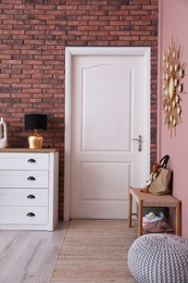 Stylish hallway interior with chest of drawers and bench