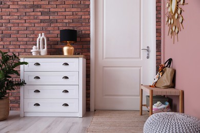 Photo of Stylish hallway interior with chest of drawers and bench