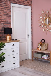 Photo of Stylish hallway interior with chest of drawers and bench