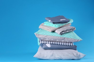 Stack of clean bed sheets and pillows on blue background. Space for text