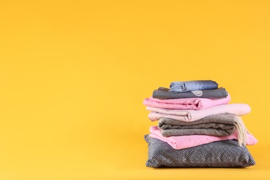 Photo of Stack of clean bed linen and pillow on yellow background. Space for text