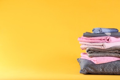 Photo of Stack of clean bed linen and pillow on yellow background. Space for text