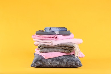 Stack of clean bed linen and pillow on yellow background. Space for text