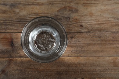 Photo of Glass of soda water on wooden table, top view. Space for text