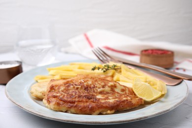 Photo of Tasty soda water battered fish, potato chips and lemon slice served on white textured table