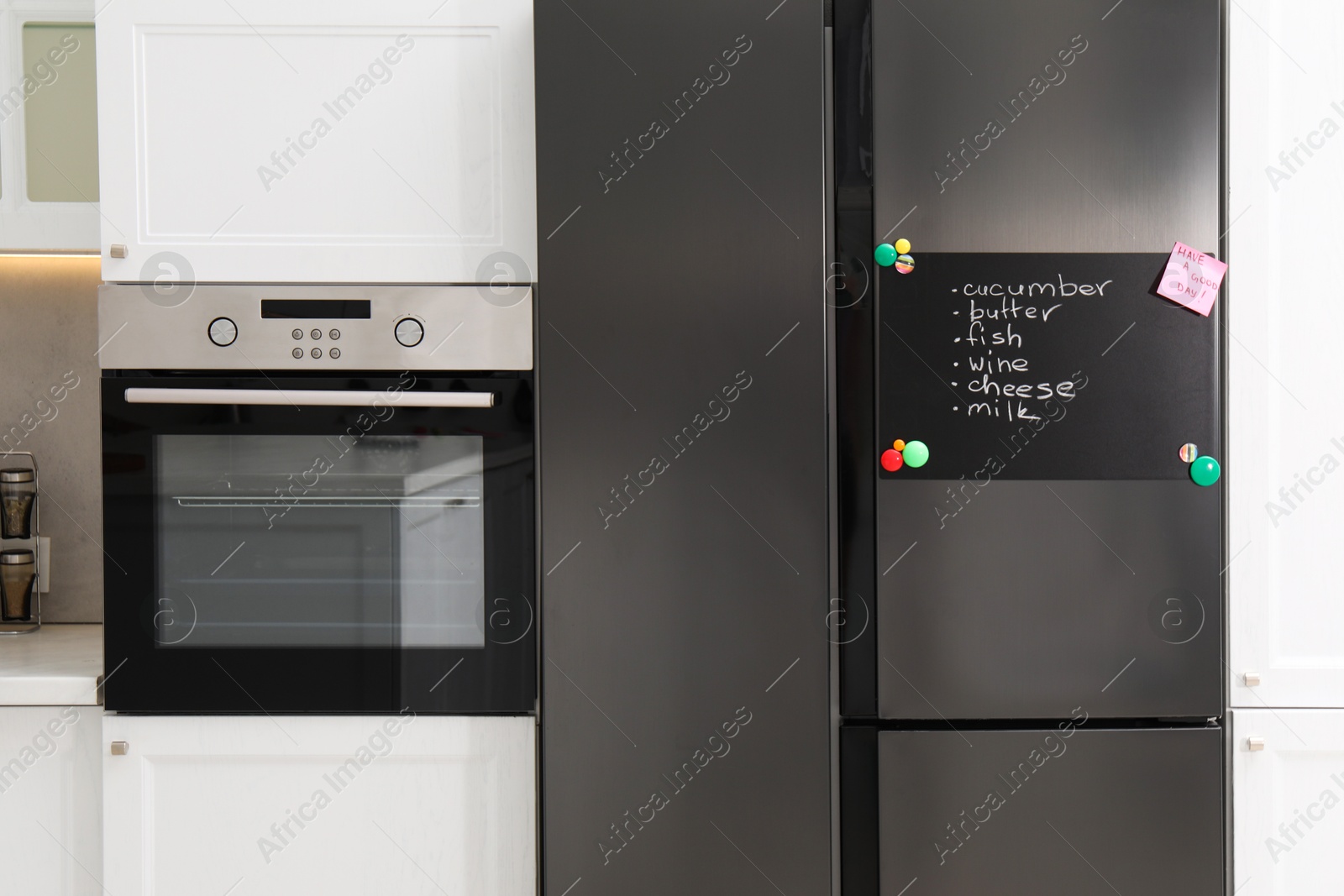 Photo of Magnetic board with shopping list and note on refrigerator in kitchen