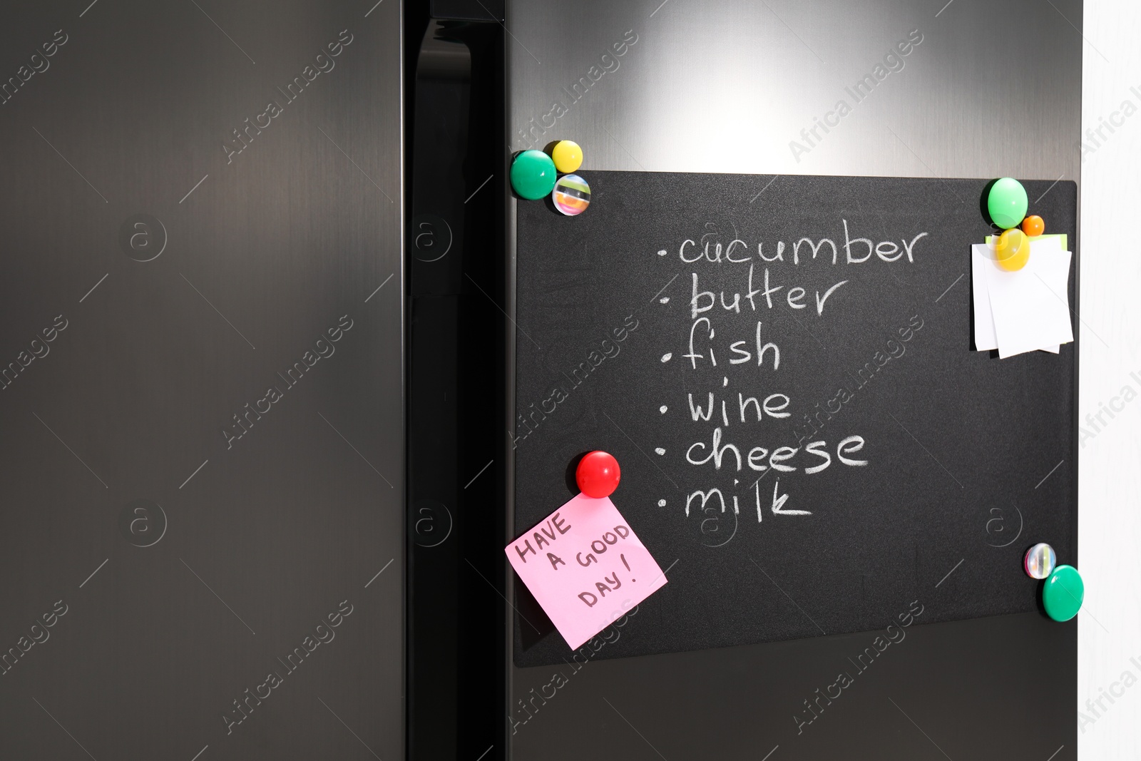 Photo of Magnetic board with shopping list and notes on refrigerator in kitchen