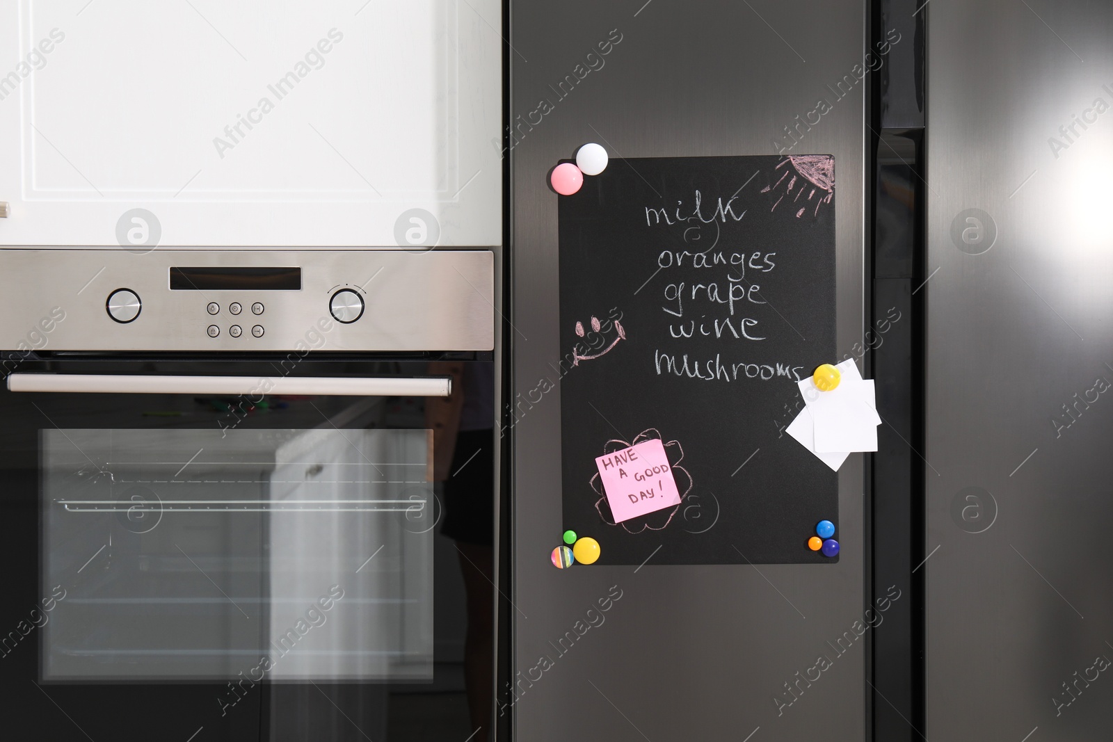 Photo of Magnetic board with shopping list and notes on refrigerator in kitchen