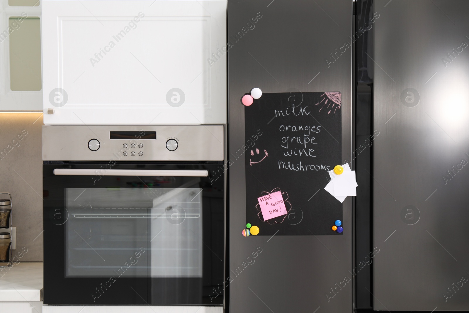 Photo of Magnetic board with shopping list and notes on refrigerator in kitchen