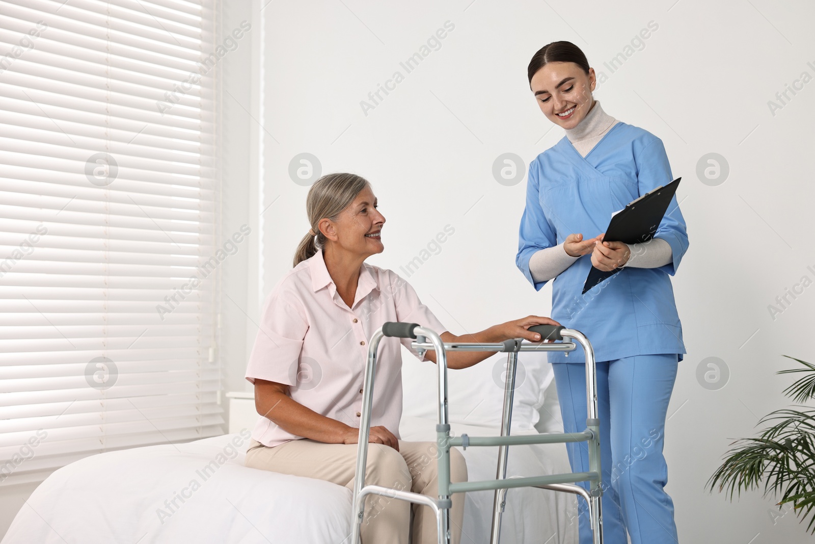 Photo of Nurse helping senior woman with walking frame in clinic