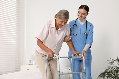 Nurse helping senior woman with walking frame in clinic