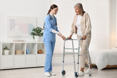 Nurse helping senior woman with walking frame in clinic