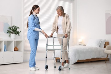 Nurse helping senior woman with walking frame in clinic